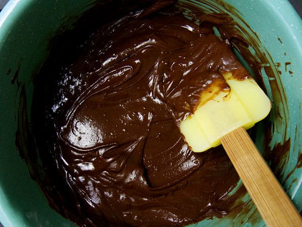 chocolate chips and melted butter in a green bowl being stirred with a spatula