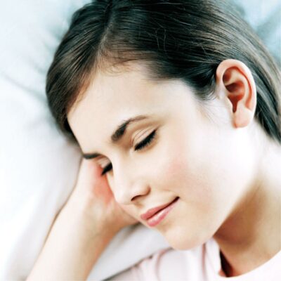 A young woman with closed eyes is lying on her side, resting her head on a pillow and appearing relaxed, as if she’s cleaning in your sleep.