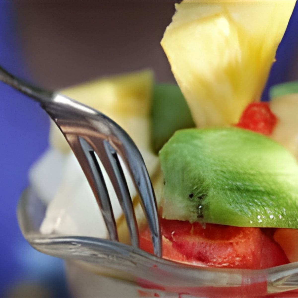 A close-up of a fork with pieces of kiwi, pineapple, and watermelon in a glass dish—a delicious inspiration for those learning how to eat healthy for life.