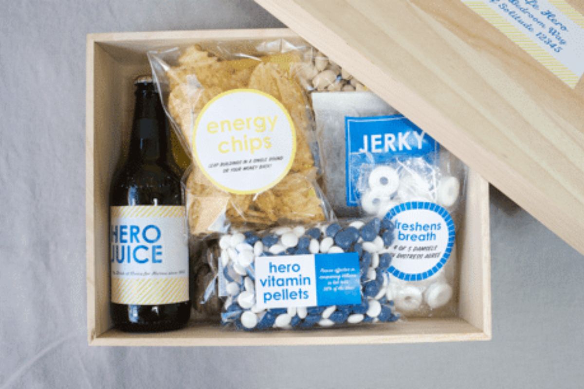Open wooden gift box with snacks and a bottled drink.