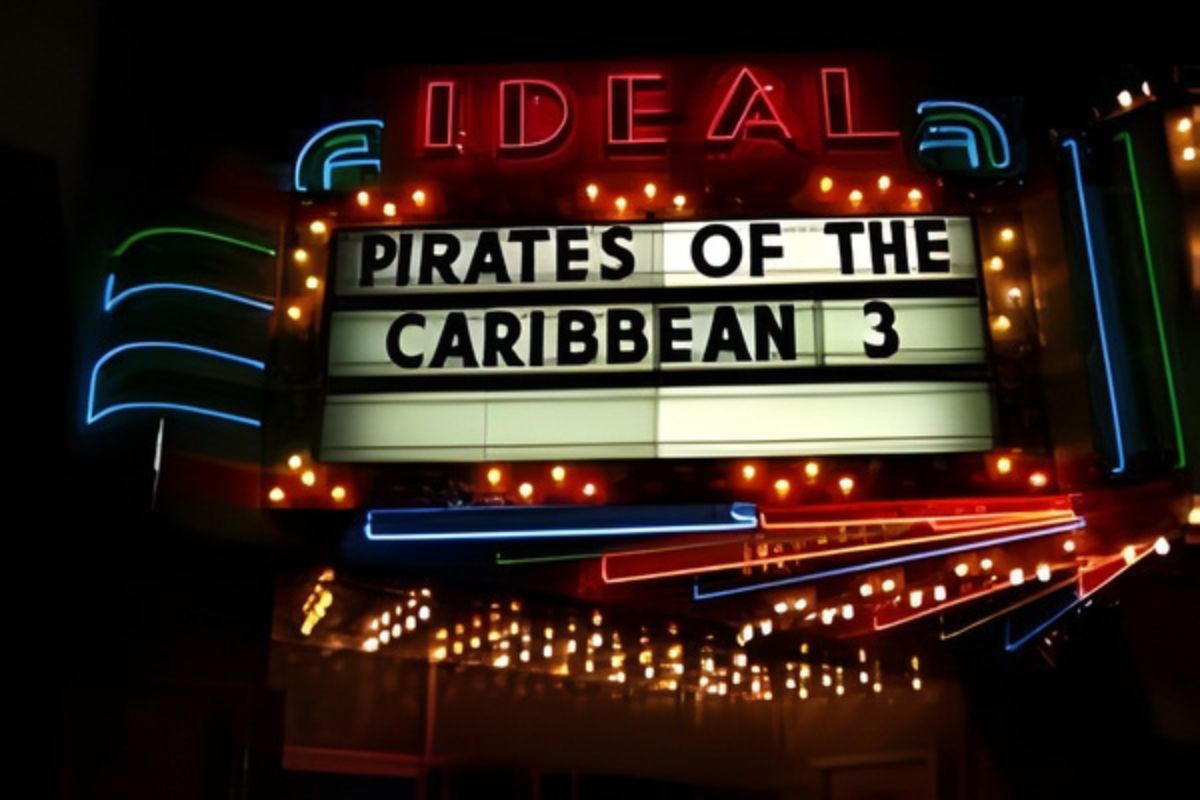 Now Showing Neon-lit theater marquee displaying "Pirates of the Caribbean 3" at night, with the word "IDEAL" illuminated above.