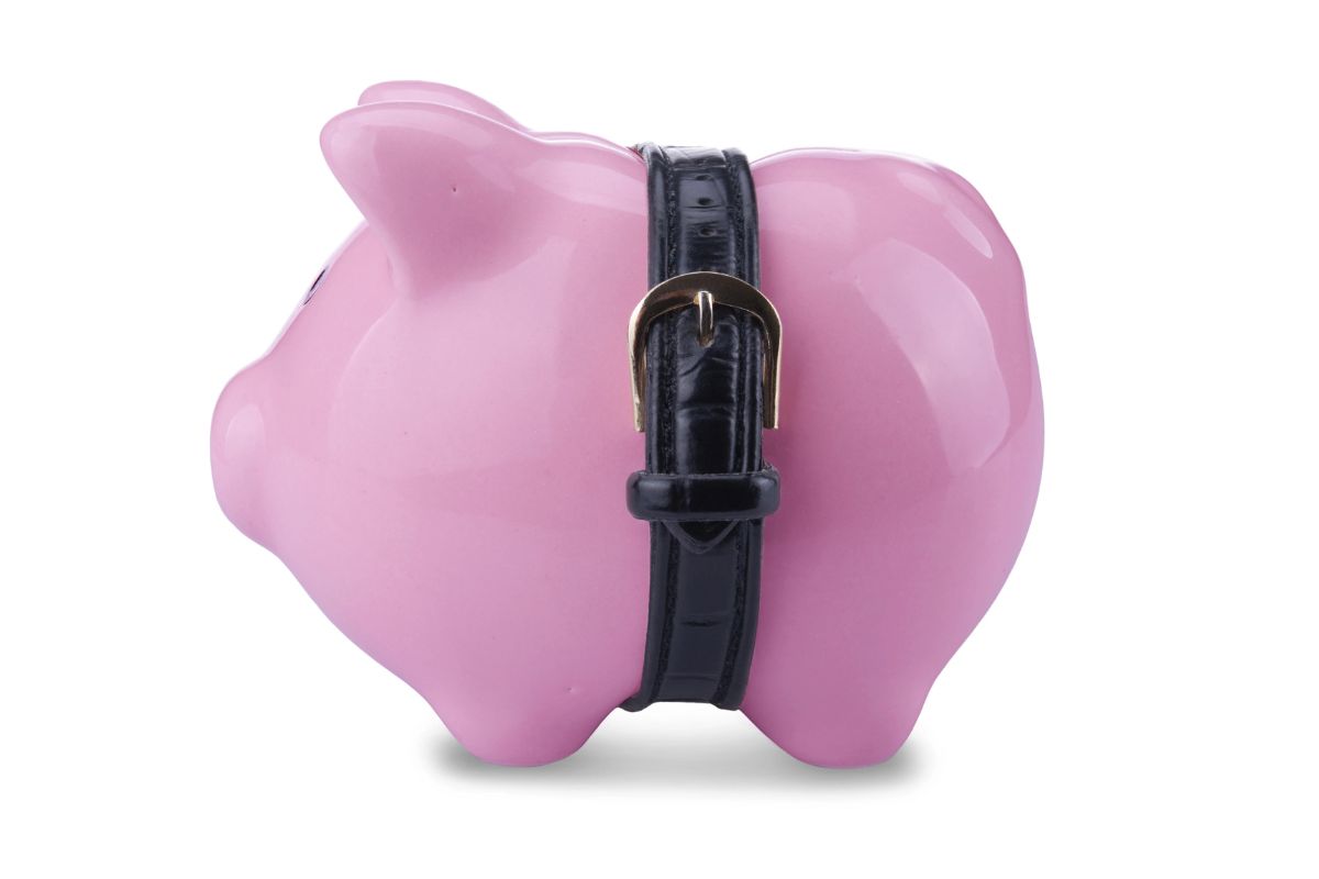 Pink piggy bank with a black leather belt strapped around its body, photographed against a white background-perfect for saving up while planning your top 10 family dinners under 10.