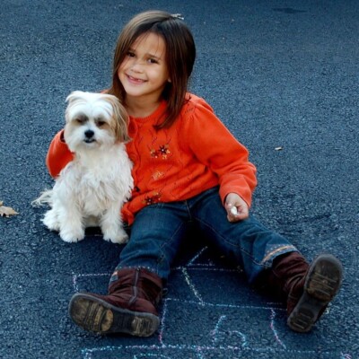 little girl holding puppy dog outside