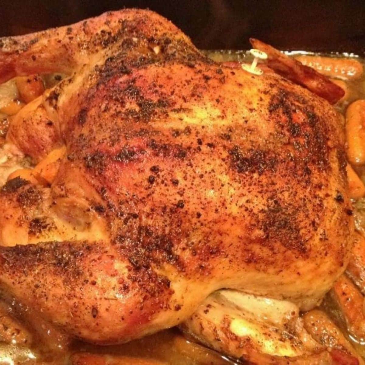 Easy, delicious roasted chicken with crispy, seasoned skin surrounded by tender cooked carrots in a baking dish.