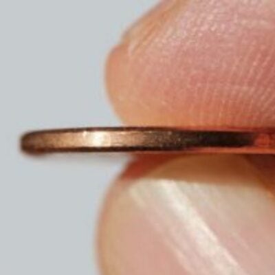 A close-up of two fingers holding a thin copper-colored coin by its edge against a plain background, capturing a simple moment of saving.
