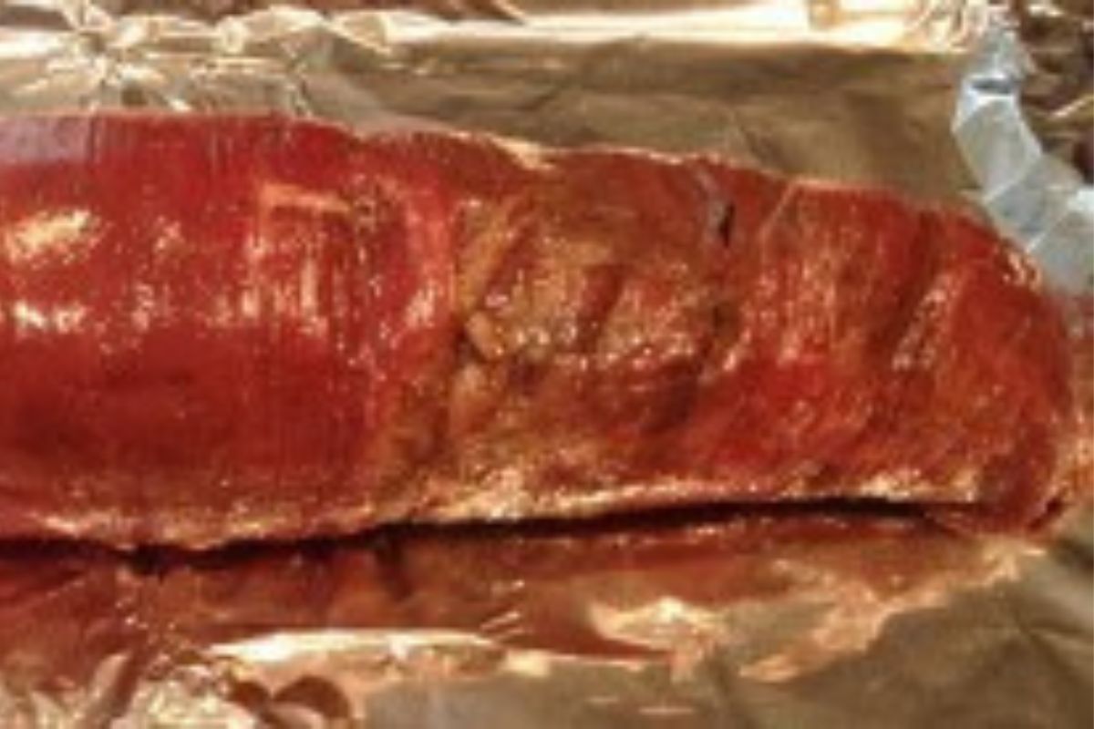 Rolled flank steak on a foil-lined baking sheet.
