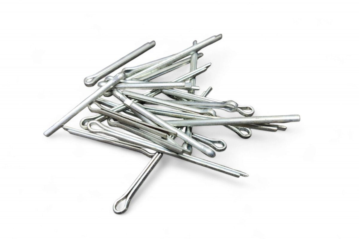 A pile of silver metal cotter pins is arranged on a white surface, ready for a variety of crafty uses for cotter pins.