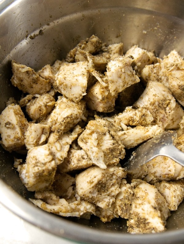 diced cooked chicken in a pot being mixed with seasonings
