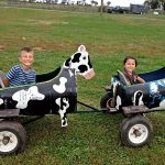 Two kids smiling on cow ride