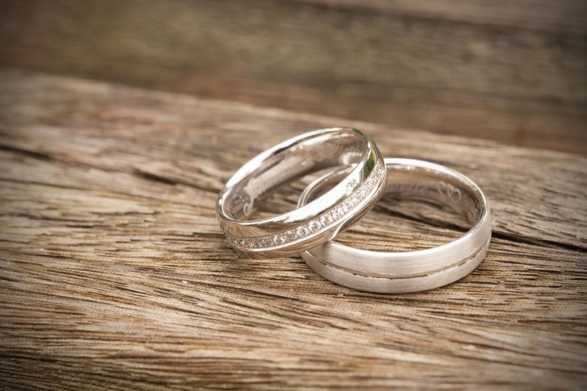 Built to last Two silver wedding rings resting on a rustic wooden surface.