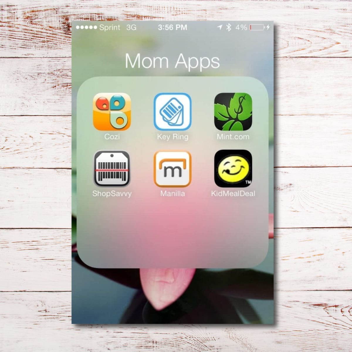 Screenshot of a smartphone folder labeled "Mom Apps" featuring six essential apps for busy moms: Cozi, Key Ring, Mint, ShopSavvy, Manilla, and KidMealDeal.