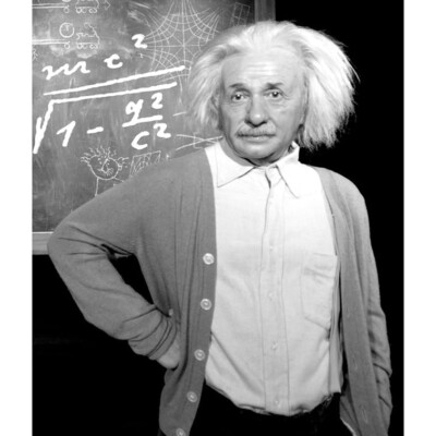 Black and white picture of Albert Einstein with his hand on his hip and a chalkboard behind him
