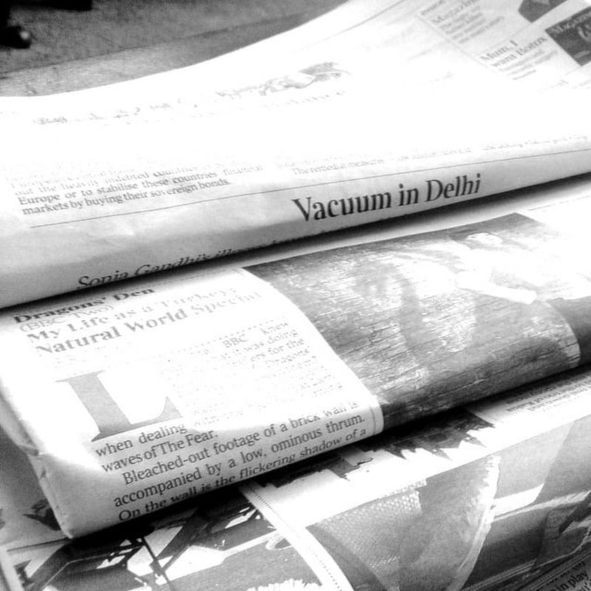A black-and-white photo of several newspapers stacked together, with one headline reading "Vacuum in Delhi" clearly visible—highlighting the many uses for newspaper beyond just delivering the news.