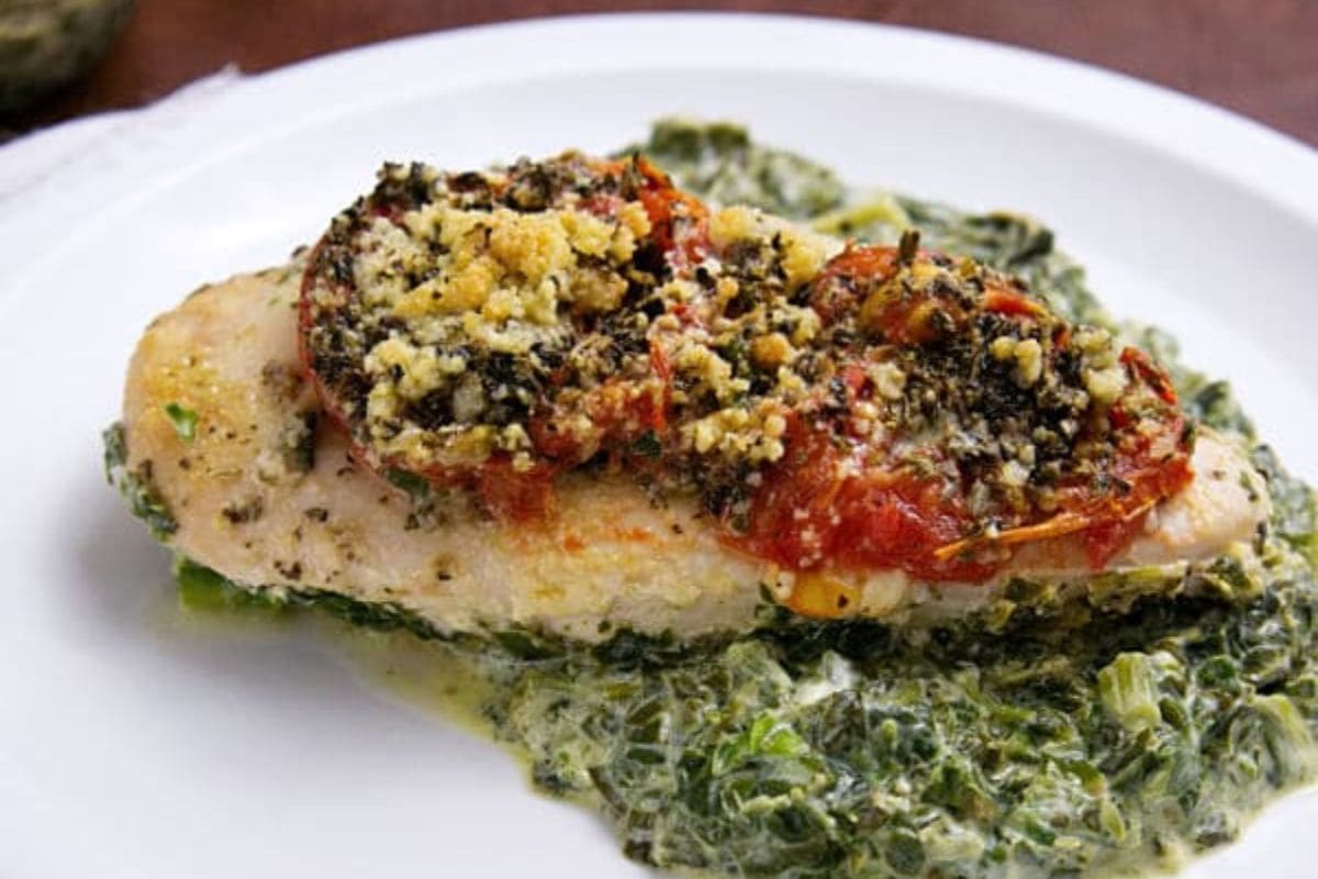 A delicious chicken florentine bake features baked chicken breast topped with tomatoes, and herbs.