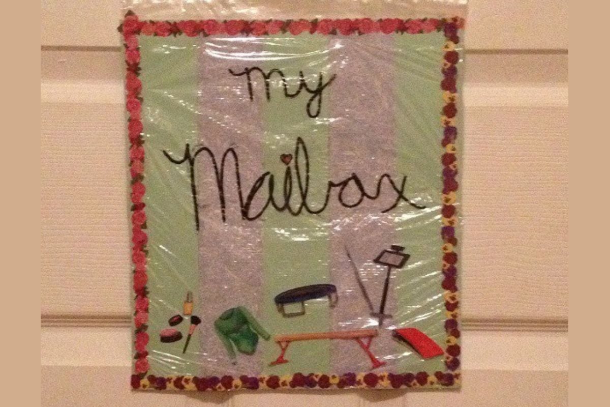 A handmade sign reading "My Mailbox" with illustrations of gardening tools, a bench, and gloves, bordered with a heart pattern, adds charm to the door-perfect for organizing family mailboxes.