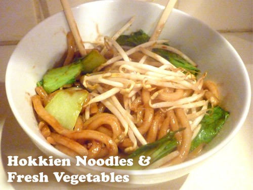 Hokkien Noodles and fresh vegetables in a white bowl with chopsticks in it