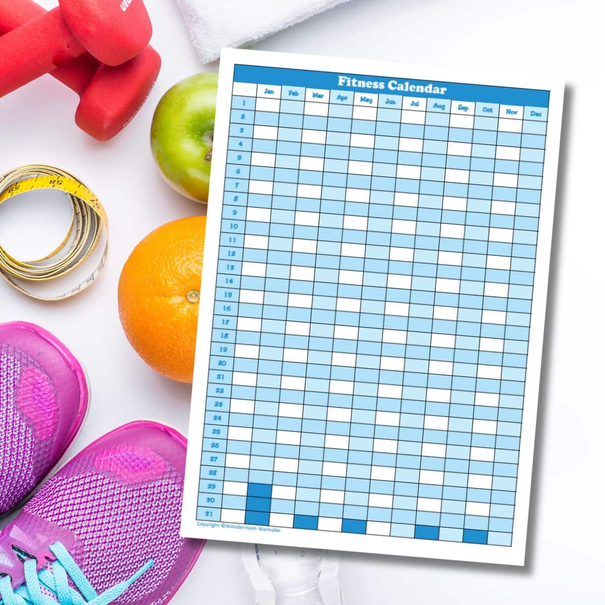 A blank fitness calendar is placed on a white surface next to pink dumbbells, measuring tape, green apple, orange, pink running shoes, and a towel—everything you need to plan and improve your fitness.