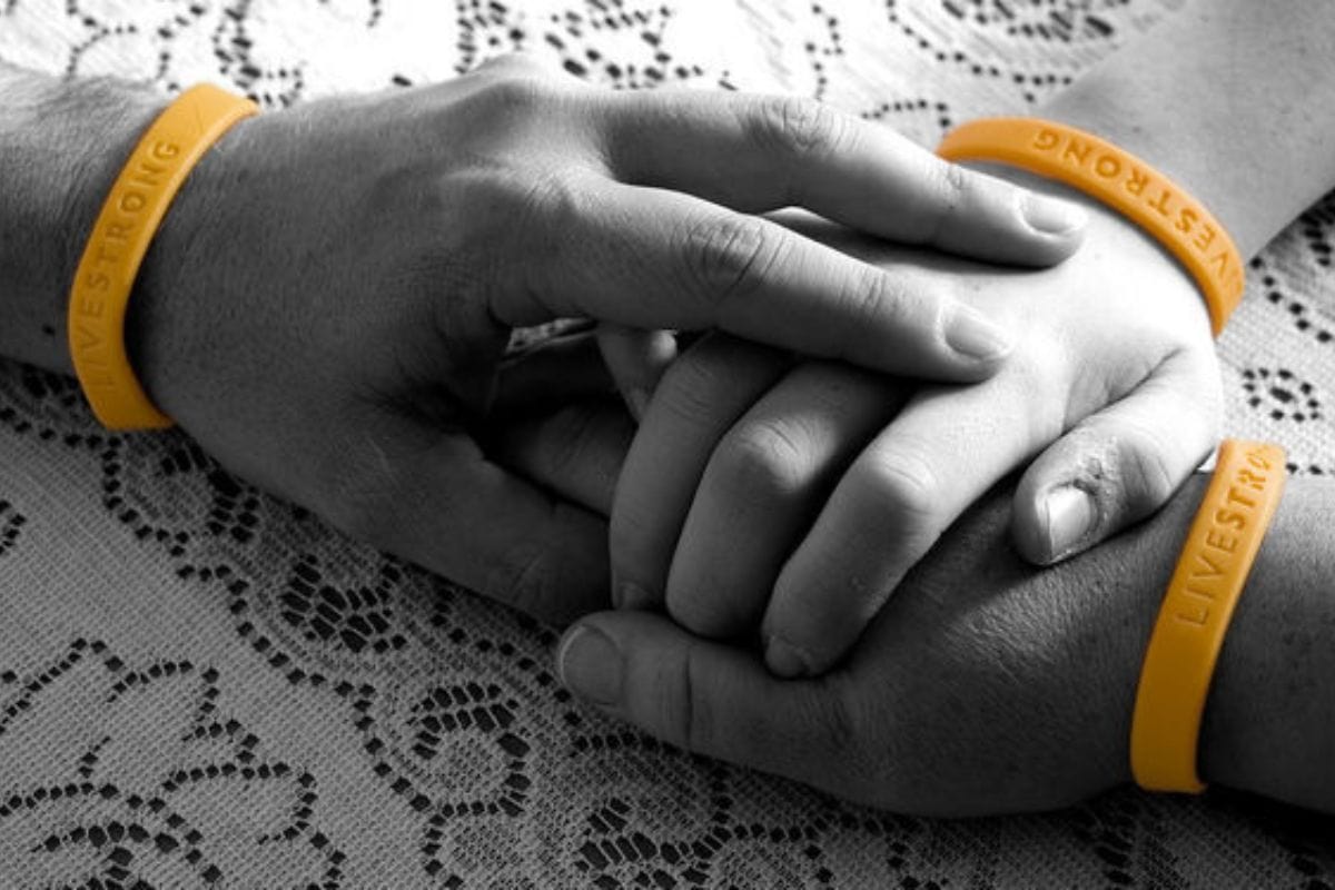 We're thinking of you Three hands wearing yellow LIVESTRONG wristbands, united in support of cancer awareness.