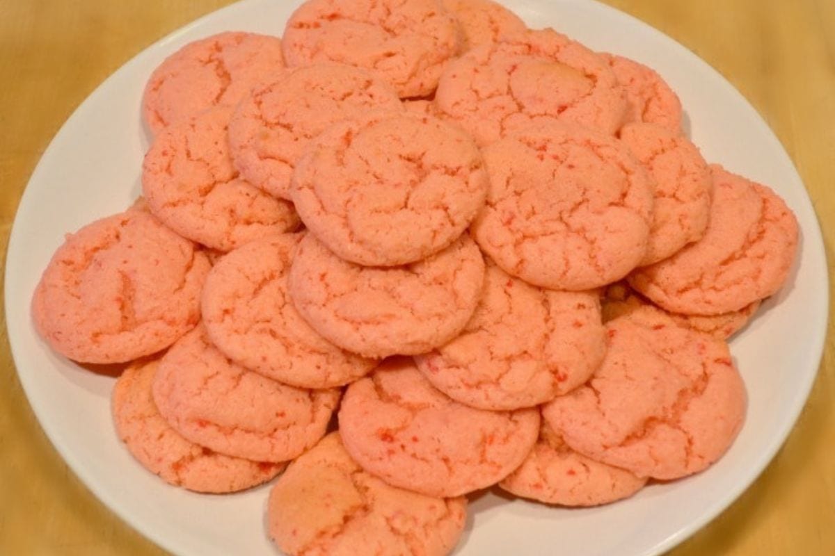 Strawberry Cake Mix Cookies on a white plate on a brown table.