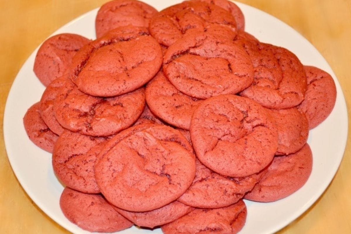 Red Velvet Cake Mix Cookies on a white plate on a brown table.