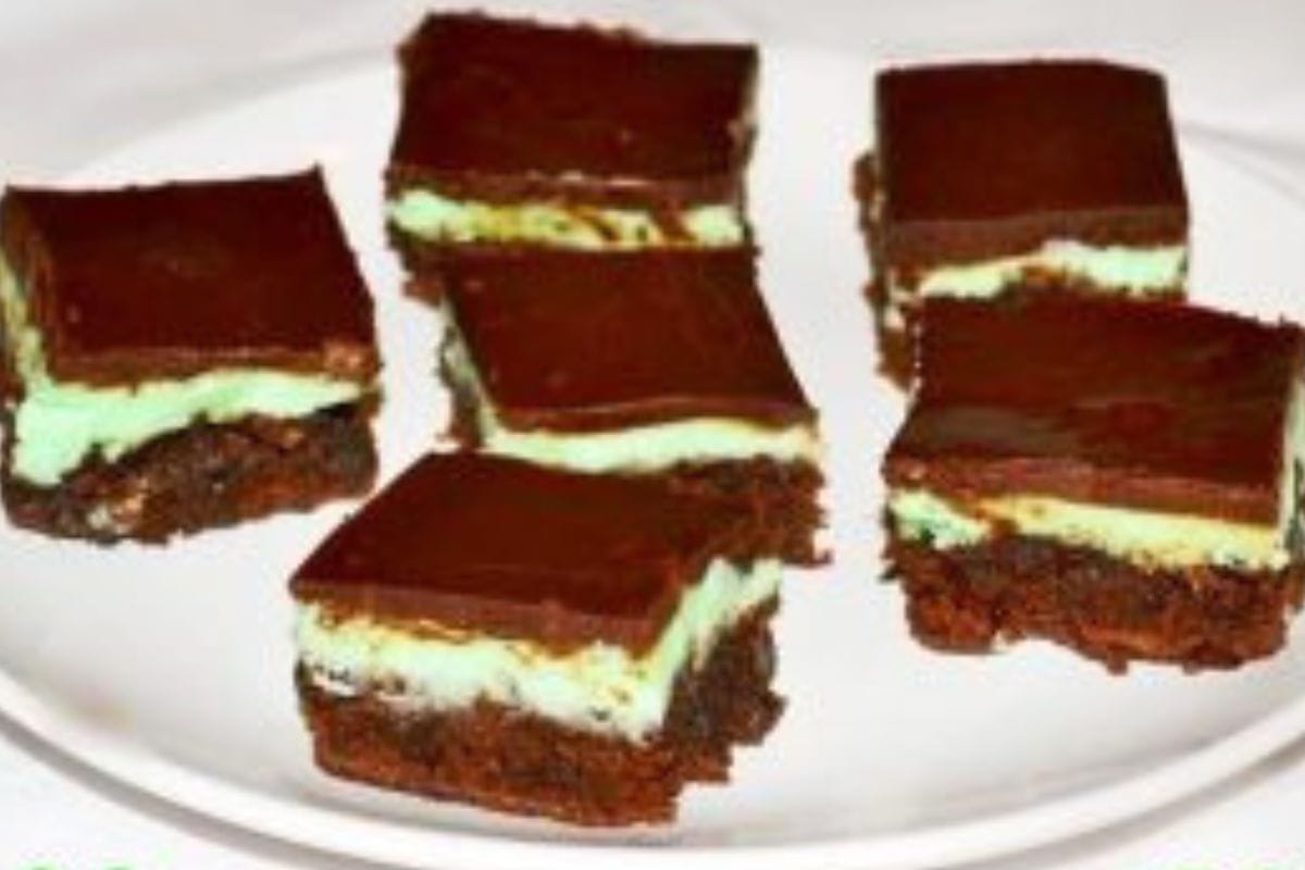 A white plate with six creme de menthe brownies, each featuring a green mint layer between rich chocolate layers.