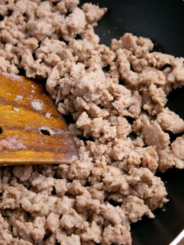 a wooden spatula stirring ground turkey cooking in a skillet