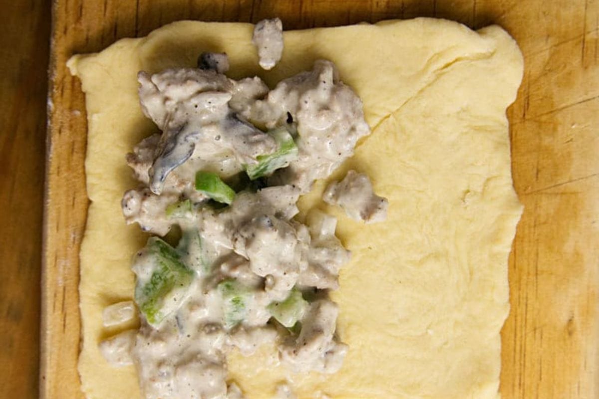 Turkey mixture on half of the dough on a wooden cutting board.