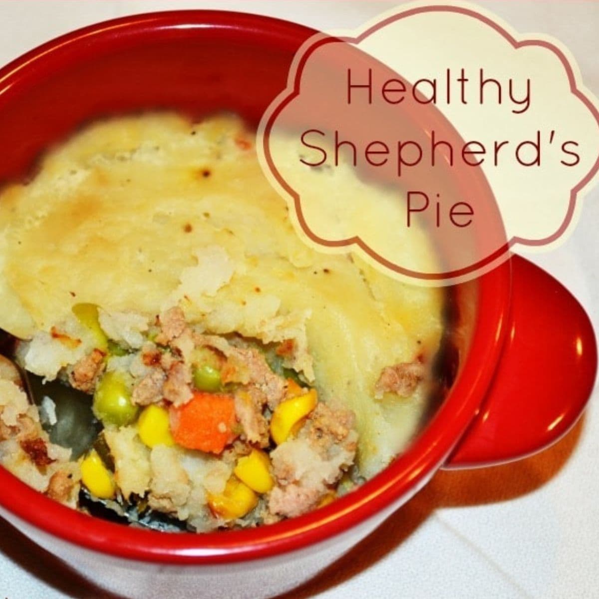 A red bowl filled with healthy shepherd’s pie, featuring creamy mashed potatoes on top and a hearty mix of vegetables and ground meat beneath. Text overlay reads "Healthy Shepherd's Pie.