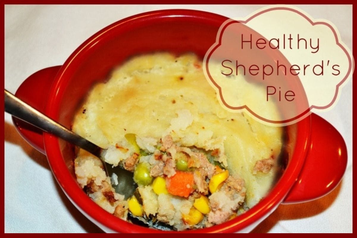 A red bowl filled with healthy shepherd's pie, with a spoon inside.