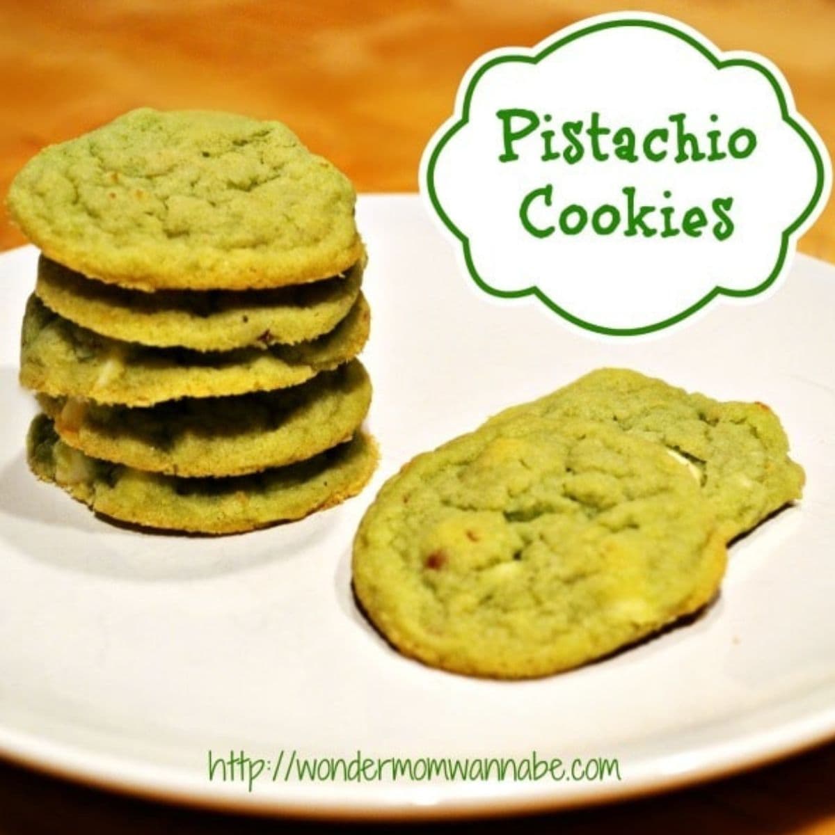 A plate with a stack of green pistachio cookies and two beside it. The text "Pistachio Cookies" highlights these delicious pistachio cookies, with the website URL featured at the bottom.