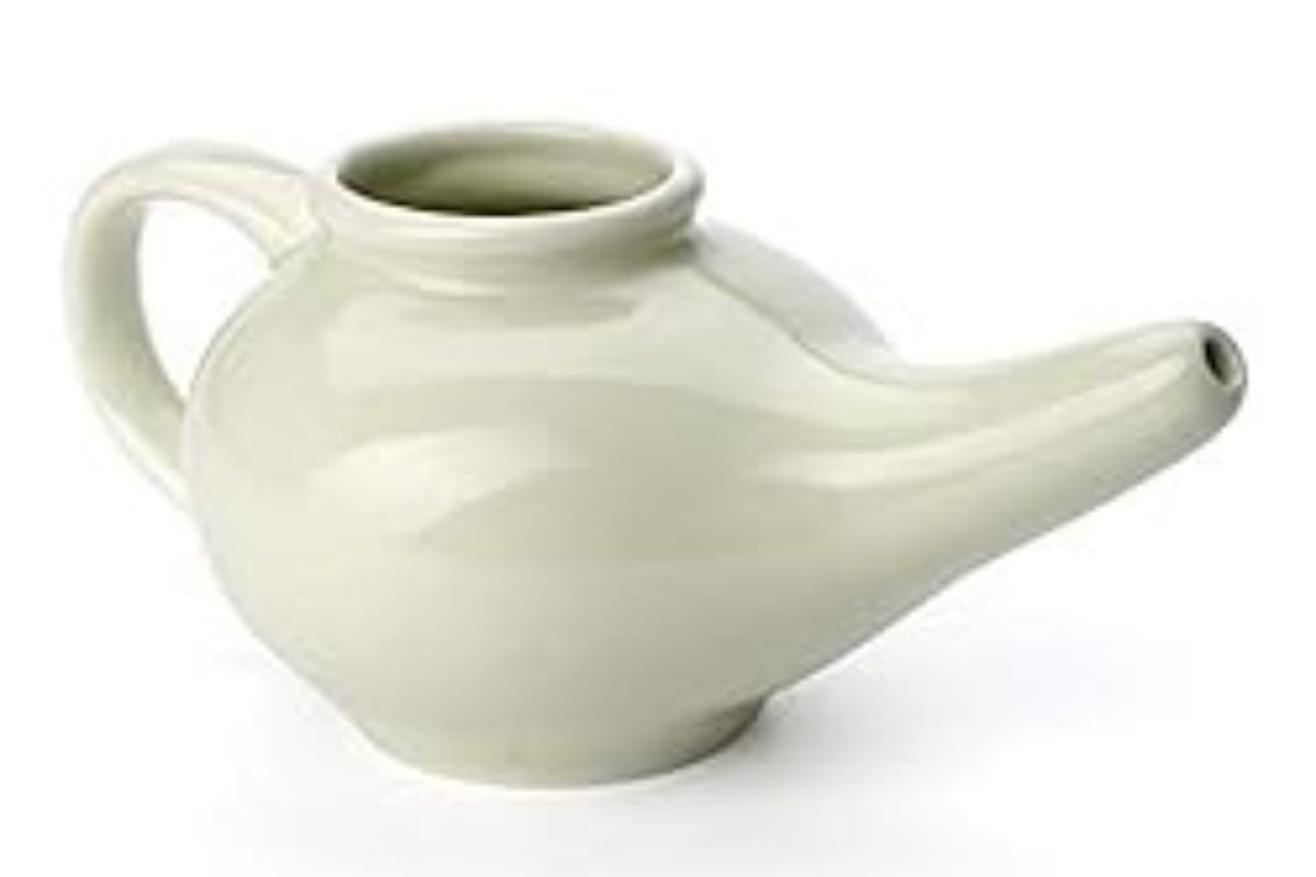 A white ceramic Zarbee's neti pot with a handle on one side and a spout on the other, used for gentle nasal irrigation.