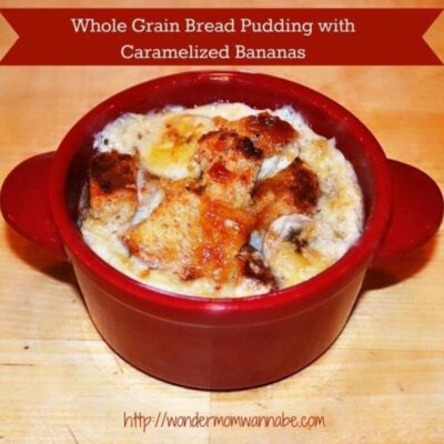 A red ramekin filled with whole grain Roman Meal bread pudding topped with caramelized bananas sits on a wooden surface. Text above reads: "Whole Grain Bread Pudding with Caramelized Bananas.