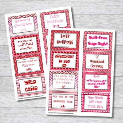 Two sheets of free printable love coupons with red and pink borders, featuring rewards like breakfast in bed, foot massage, and guilt-free guys night, displayed on a wooden surface.