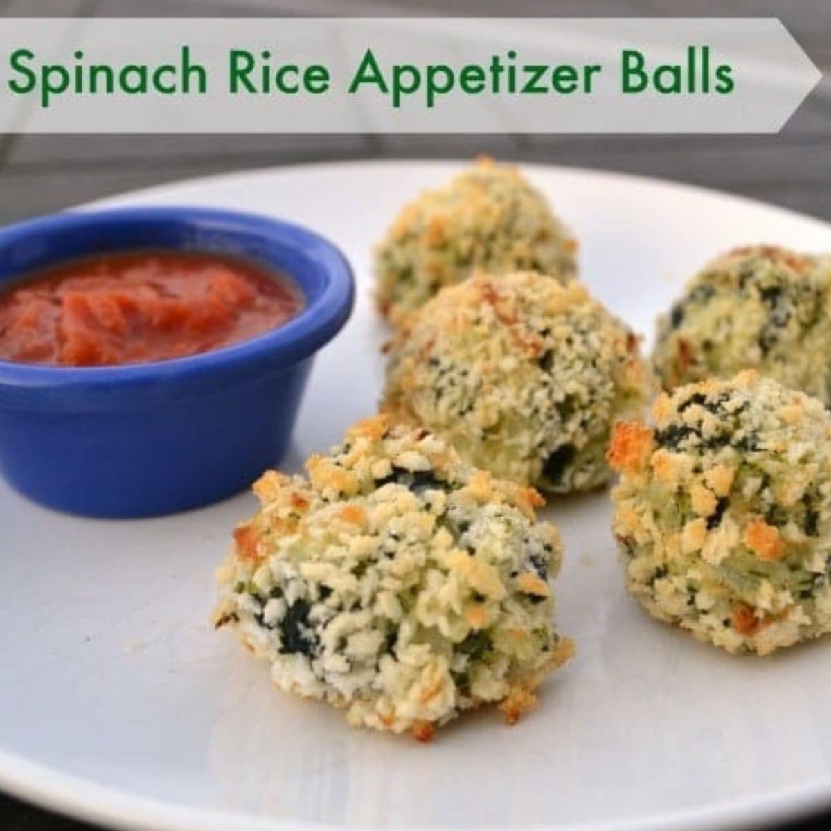 Four spinach rice appetizer balls arranged on a white plate beside a small blue cup of red dipping sauce. At the top, text reads "Spinach Rice Appetizer Balls," highlighting this flavorful vegetarian snack.