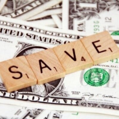Wooden Scrabble tiles spelling "SAVE" are placed on scattered U.S. dollar bills, highlighting ways to save money on your utility bills.