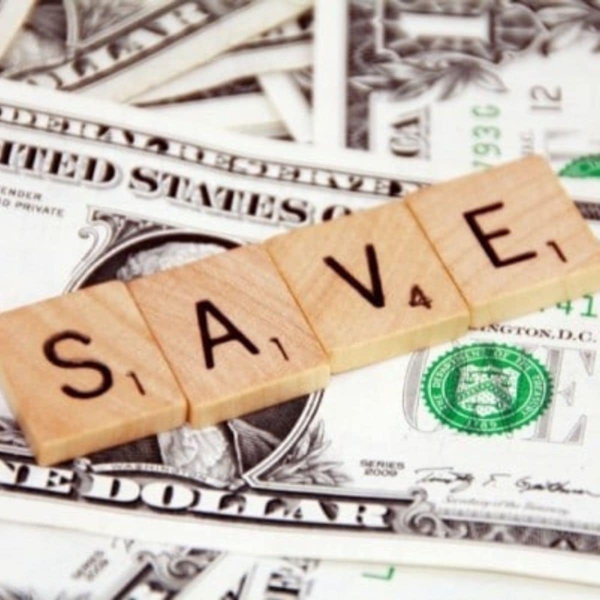 Wooden Scrabble tiles spelling "SAVE" are placed on scattered U.S. dollar bills, highlighting ways to save money on your utility bills.