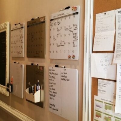 A wall with several whiteboard calendars and organizers, alongside a corkboard holding notes and papers, creates an organized home space perfect for planning and scheduling.