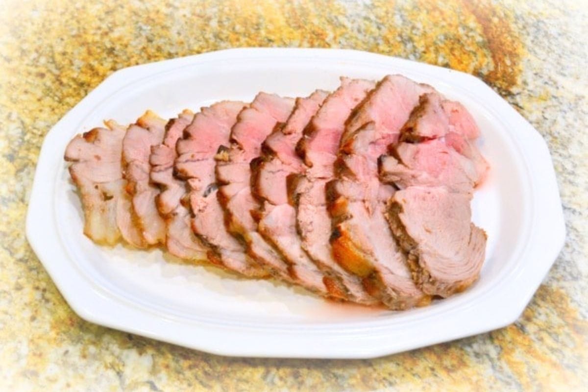 Sliced roast pork arranged on a white oval plate.