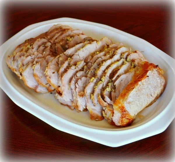 Herb Roasted Pork Loin on a white platter on a brown table