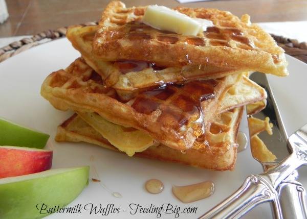 a stack of Buttermilk Waffles next to apple slices on a white plate