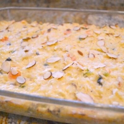 A glass baking dish filled with creamy garden chicken casserole, topped with sliced almonds.