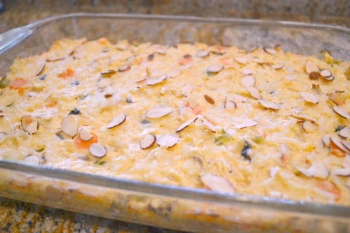 A glass baking dish filled with creamy garden chicken casserole, sits on a granite countertop.