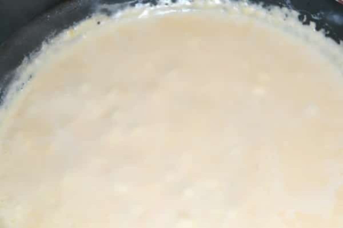 A close-up of a pot or pan filled with a creamy, light beige sauce.