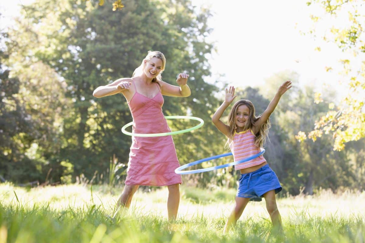 A mother and daughter enjoying a playful game of hula hoops outdoor.