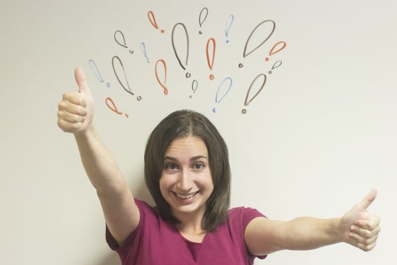 a lady with both thumbs up standing against a wall with exclamation marks drawn on it after she tried 3 Simple Tricks to Instantly Improve Your Mood