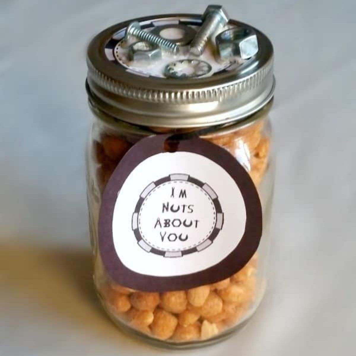 A jar filled with peanuts, labeled "I’m nuts about you," with metal nuts and bolts on the lid—a clever DIY Father's Day Gift that shows your appreciation with a fun twist.