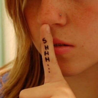 A person holds a finger to their lips with "SHHH..." written on the finger, gesturing for silence—a subtle reminder of why you should not confide in your child.