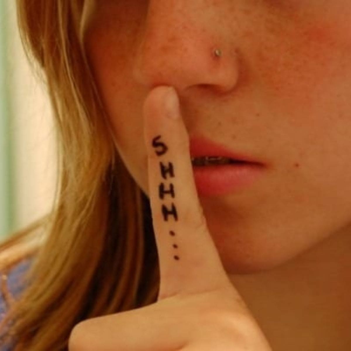 A person holds a finger to their lips with "SHHH..." written on the finger, gesturing for silence—a subtle reminder of why you should not confide in your child.