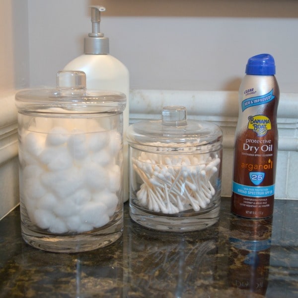 Banana Boat Dry Oil Clear UltraMist Sunscreen next to qtips, cotton balls, and lotion on a counter