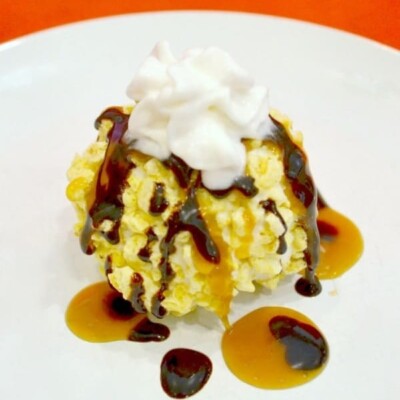 Crunchy ice cream on white plate with chocolate and caramel syrup and whipped cream